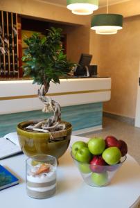 a table with a bonsai plant and a bowl of apples at Grand Hotel Terme in Margherita di Savoia
