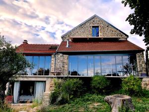a house with large glass windows on the front of it at Domaine de Combraille en Marche in Saint-Médard