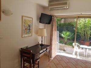 um quarto com uma secretária, uma televisão e uma janela em Hotel La Cle Du Sud em Le Cannet