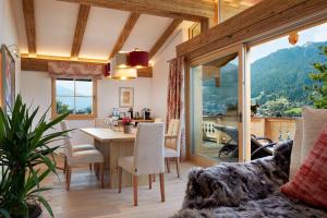 a living room with a table and a dining room with a view at Tennerhof Luxury Chalets in Kitzbühel