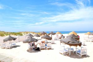 einen Strand mit Liegestühlen und Sonnenschirmen am Strand in der Unterkunft Lisbon Beach Apartments 5 in Costa da Caparica