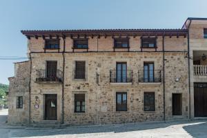 um antigo edifício de tijolos com janelas e uma varanda em Hotel Rural Pinares de Soria em Molinos de Duero