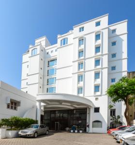 a white building with cars parked in front of it at Lemon Tree Premier “The Atrium” Ahmedabad in Ahmedabad