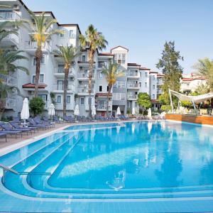 a large swimming pool with palm trees and buildings at Paloma Marina Suites - Adult Only in Kuşadası