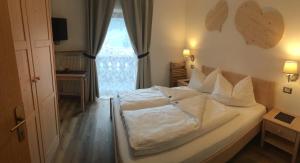 a bedroom with a large white bed with a window at Garní Nëidia in Selva di Val Gardena