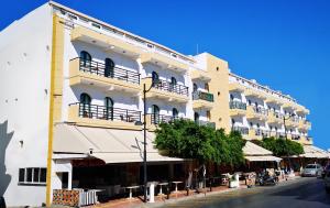 Un grand bâtiment blanc avec balcon se trouve dans une rue. dans l'établissement Pela Maria Hotel, à Chersónissos