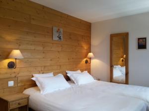 1 dormitorio con 2 camas blancas y pared de madera en Le Brabant Bar-Hôtel-Restaurant, en La Bresse