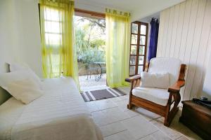 a bedroom with a bed and a chair and a window at Uma Casa a Beira Sol in Lagos