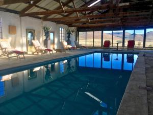 a swimming pool in a house with chairs and windows at Sneeuberg Nature Reserve in Nieu-Bethesda