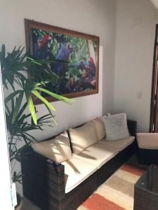 eine Couch in einem Wohnzimmer mit einem Gemälde an der Wand in der Unterkunft Casa a 100mts da praia in Ilhabela