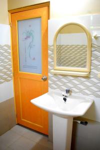 a bathroom with a white sink and a mirror at Yaswi Guest House in Pasikuda