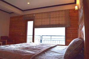 a bedroom with a bed and a large window at Hilla Apartments Nathia Gali in Abbottābād