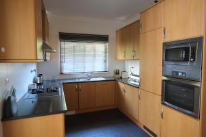 a kitchen with wooden cabinets and a sink and a microwave at Alto da Ria 37 in Alvor