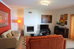 a living room with an orange couch and a tv at Alto da Ria 37 in Alvor