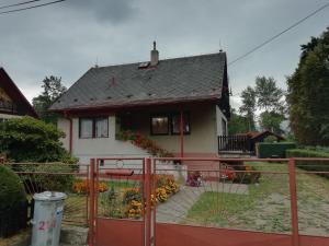 una pequeña casa con una valla roja delante de ella en Ubytování v rodinném domě en Hejnice