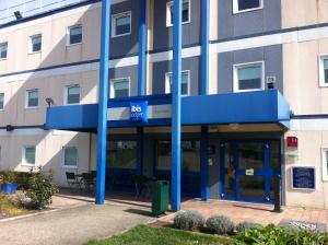 un edificio con postes azules delante de él en ibis budget Mâcon Nord en Mâcon