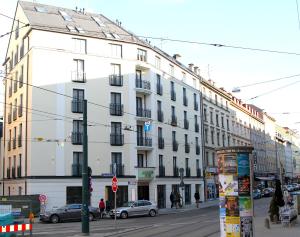 a large white building on a city street with cars at Augusten Hotel München in Munich