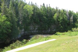 a golf course with a river next to a forest at Rocky Brook Acres in Cormack