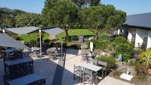 an outdoor patio with tables and chairs and trees at Logis Hotel Restaurant Le Jardin Délice in Saint-Victor +10 photos