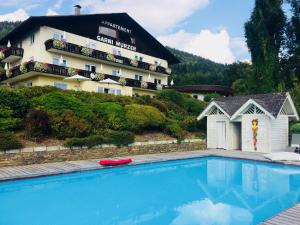 ein Hotel mit einem Pool vor einem Gebäude in der Unterkunft Hotel Garni Wurzer in Velden am Wörthersee