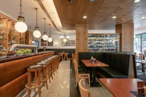 a restaurant with wooden tables and chairs and a bar at Hotel Conti Am Hauptbahnhof in M&uuml;nster