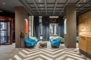 a lobby with blue chairs and tables and windows at PANORAMA Lviv Hotel in Lviv