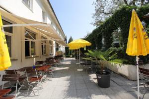 eine Terrasse mit Tischen, Stühlen und gelben Sonnenschirmen in der Unterkunft Hotel Pension Köberl in München