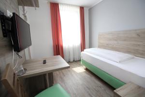 Habitación pequeña con cama y TV. en Hotel Pension Köberl en Múnich