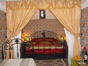 Riad Maryam Taroudant في تارودانت: غرفة نوم بسرير ولحاف احمر وستائر