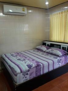 a bed with purple and white sheets and pillows at Muean Fhan Resort Aranyaprathet in Aranyaprathet