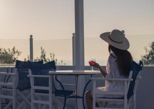 una donna seduta a un tavolo con un bicchiere di vino di Unique Galini Oia - Adults Only a Oia