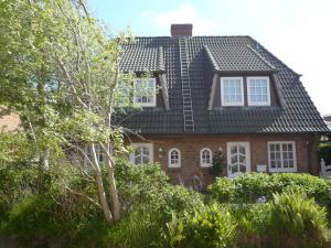 una casa de ladrillo rojo con techo negro en Kastanienhüs Apartment en Westerland