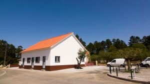 un bâtiment blanc avec un toit orange dans un parking dans l'établissement Mocho GuestHouse, à São Mamede