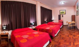 Habitación de hotel con 3 camas con colchas rojas en Hotel Colon Plaza, en Ica