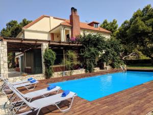 a house with a swimming pool and two lounge chairs at Promachon Villa in Foinikiá