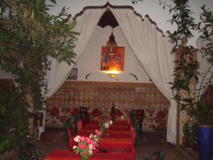 une salle de banquet avec des tables rouges et des rideaux blancs dans l'établissement Riad Maryam Taroudant, à Taroudant