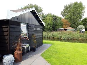 a black shed with a table and a bench in a yard at Rietzicht in Alkmaar
