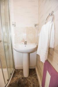 La salle de bains est pourvue d'un lavabo blanc et d'une douche. dans l'établissement Bradford Apartments, à Bradford