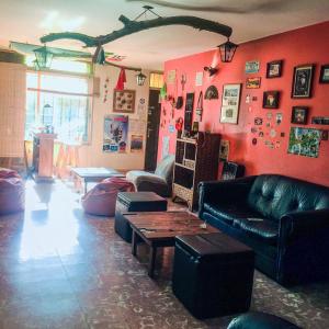 una sala de estar con paredes rojas y muebles de cuero negro. en Hostel Otro Mundo en Mendoza