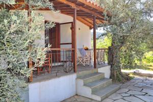 a porch of a house with a chair and a tree at Cambos Villa in Skopelos Town