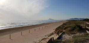 uma praia arenosa com uma cerca e o oceano em Piles playa em La Playa de la Torre de Piles