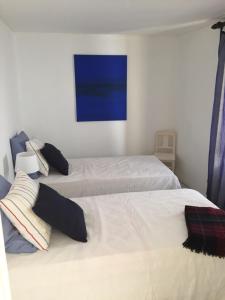 una camera con due letti e un dipinto blu sul muro di Casa dos Limoeiros a Santiago do Cacém