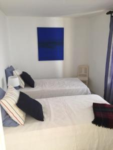 1 dormitorio con 2 camas y una pintura azul en la pared en Casa dos Limoeiros, en Santiago do Cacém