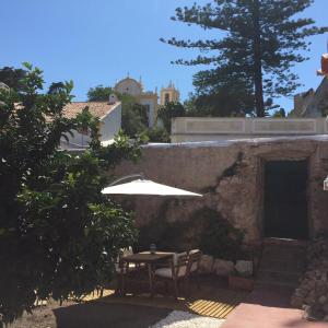 a patio with a table and an umbrella at Casa dos Limoeiros in Santiago do Cacém