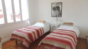 two beds in a room with white walls and windows at Appartement avec vue panoramique in Vichy