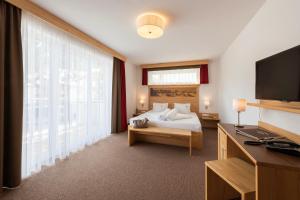 Alpinhotel Monte Superior - Silvretta Card Premium Betrieb في غالتور: غرفه فندقيه سرير وتلفزيون