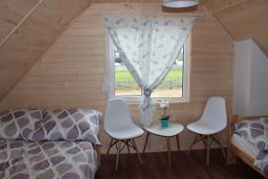 a room with a bed and chairs and a window at Biały Łabędź in Wilków