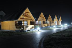 uma fila de casas de madeira à noite com luzes em Biały Łabędź em Wilków