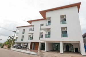 Un grand bâtiment blanc avec des fenêtres donne sur une rue. dans l'établissement Bed Tel, à Ban Kaeo