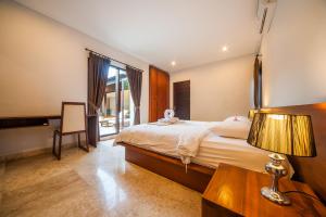 a hotel room with a bed and a table with a lamp at Tirta Villa in Sanur